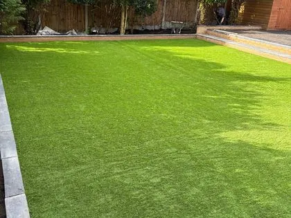New artificial lawn with paved edging in a landscaped back garden