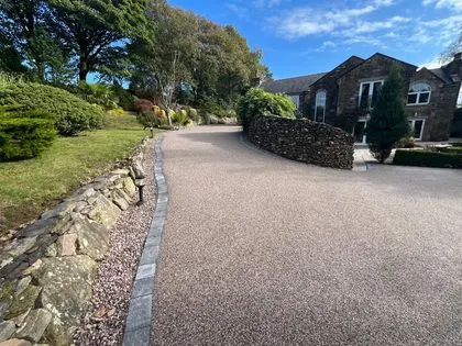 Curved resin bound driveway with stone walls and landscaped borders