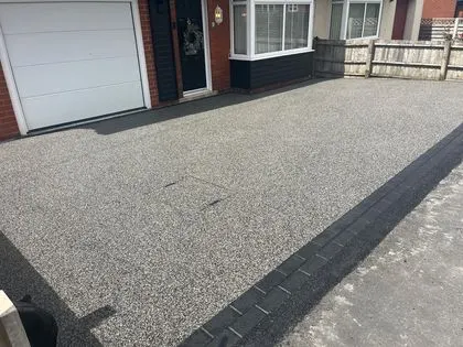Light grey resin bound driveway with dark block edging